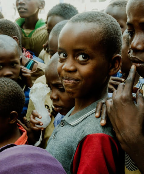 A young man in children's home smiling at the camera i for you